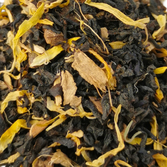 Heap of black tea leaves with yellow elements on a white background